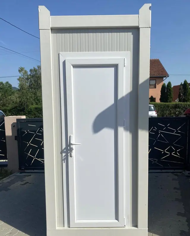 White deluxe flushing restroom cabin with a single door on a paved driveway