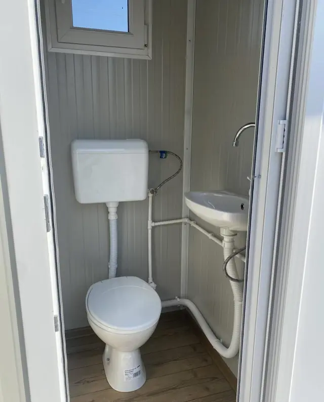 Flushing toilet with tank and a small wall sink inside a deluxe cabin