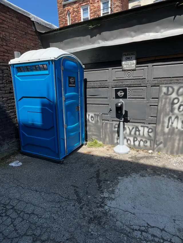 Porta potty and handwash station in a paved alley