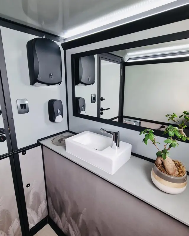 Restroom trailer sink with towel and soap dispensers and a mirror