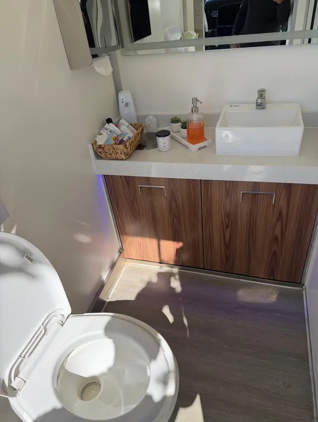 Restroom trailer vanity with a vessel sink, wood cabinet and toiletries